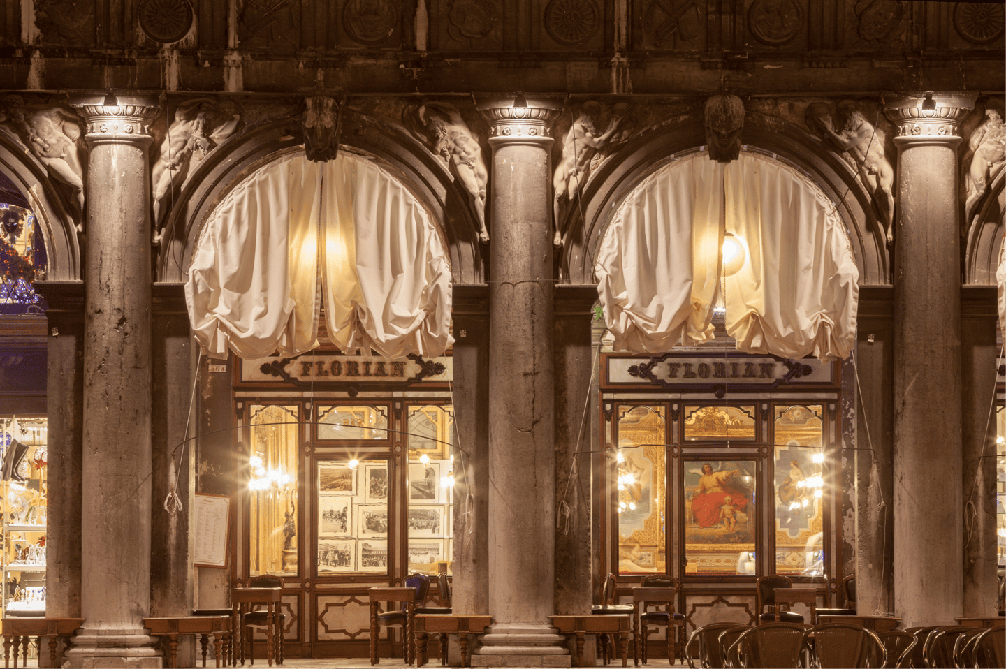 Exterior view of the historic Caffe Florian in St. Mark's Square, Venice, featuring arched windows and ornate stone columns.