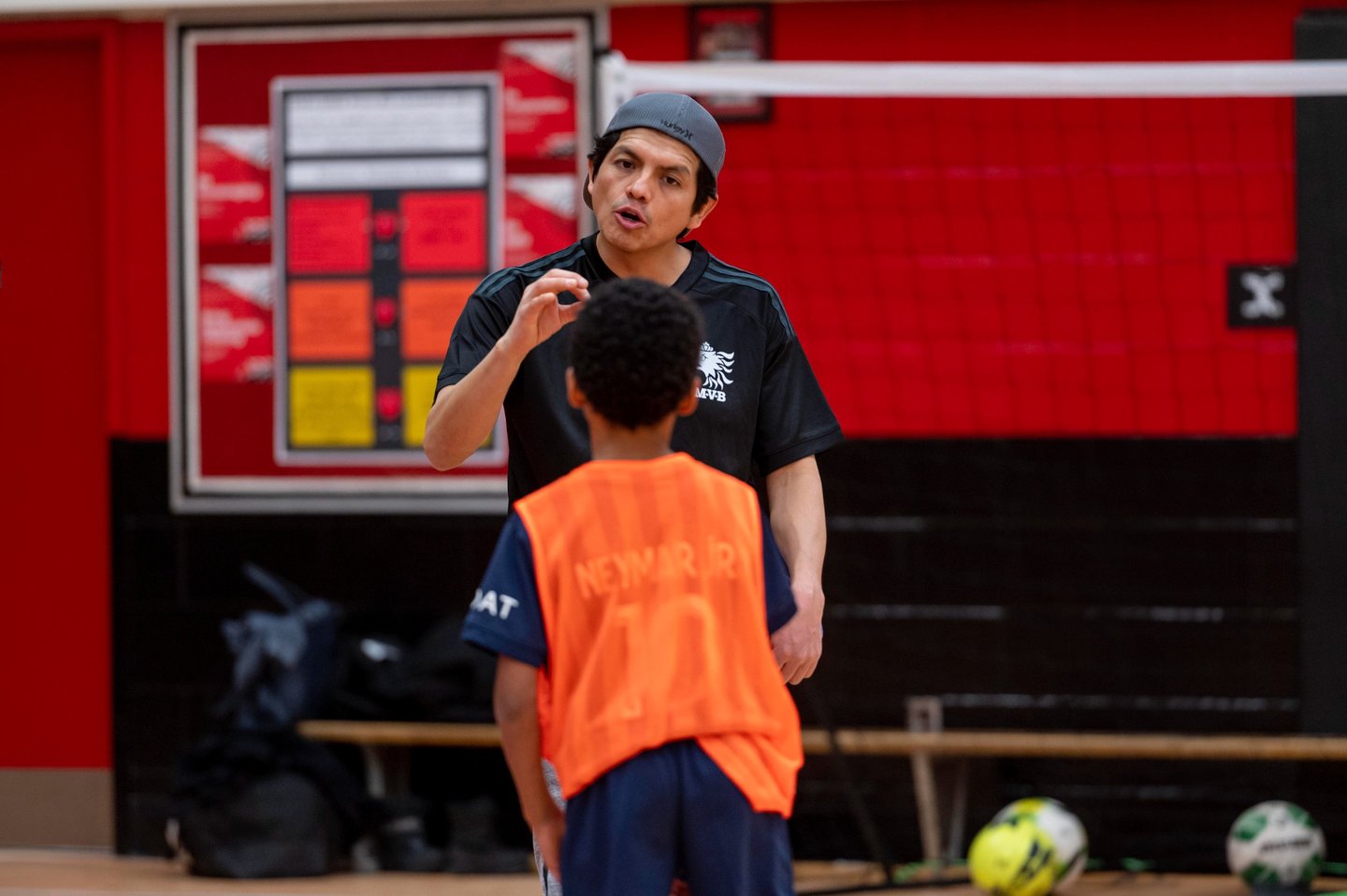 A MVB FC soccer coach instructs a young player indoor in Mississauga