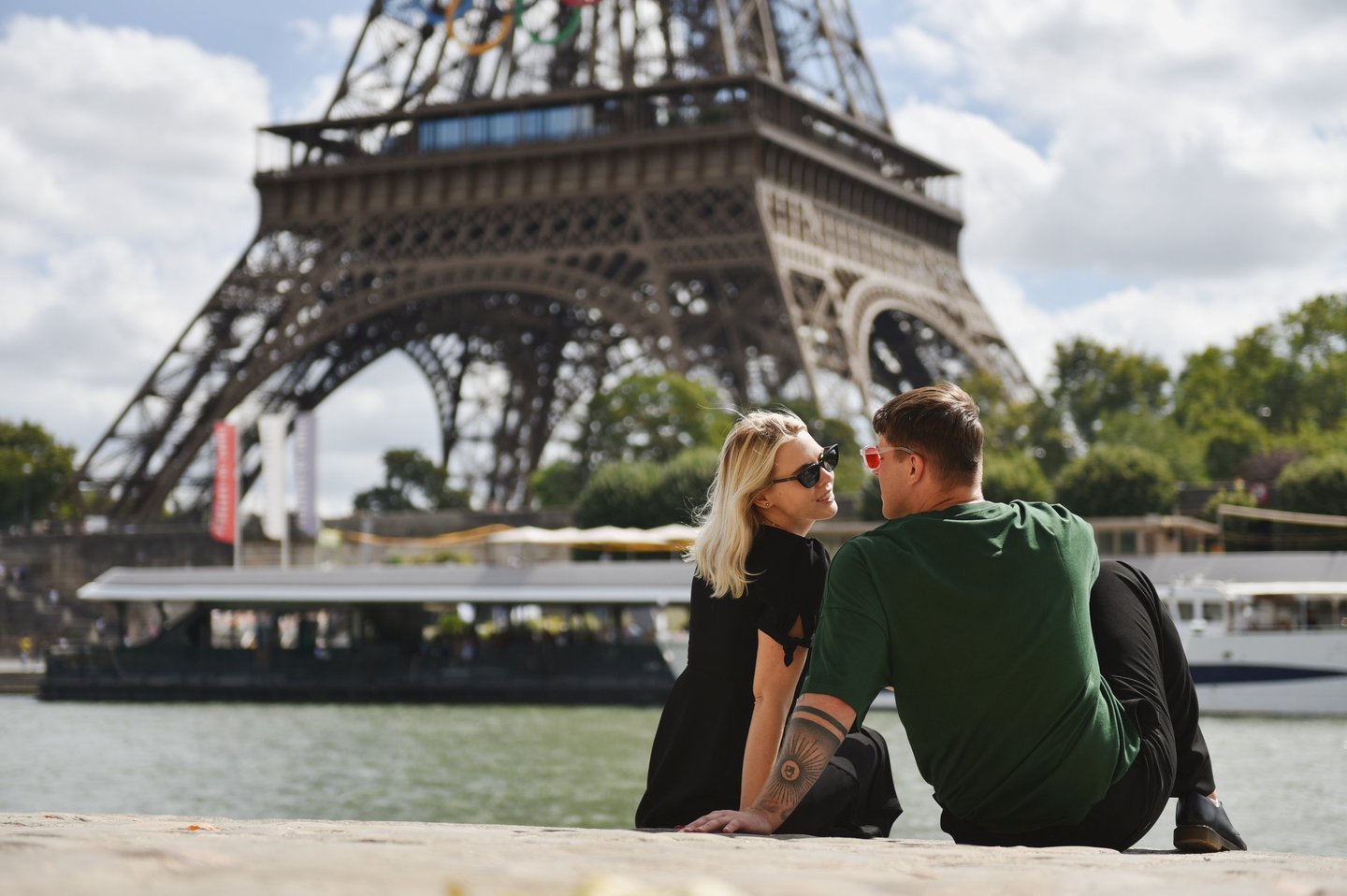 A Paris face à la tour Eiffel, deux amoureux sont assis sur les bords de Seine
