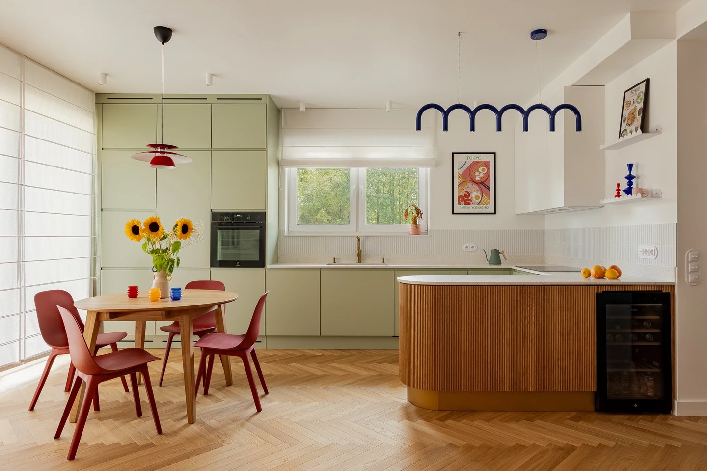 Fotografia wnętrz: szałwiowa kuchnia z wyspą i czerwone akcenty.