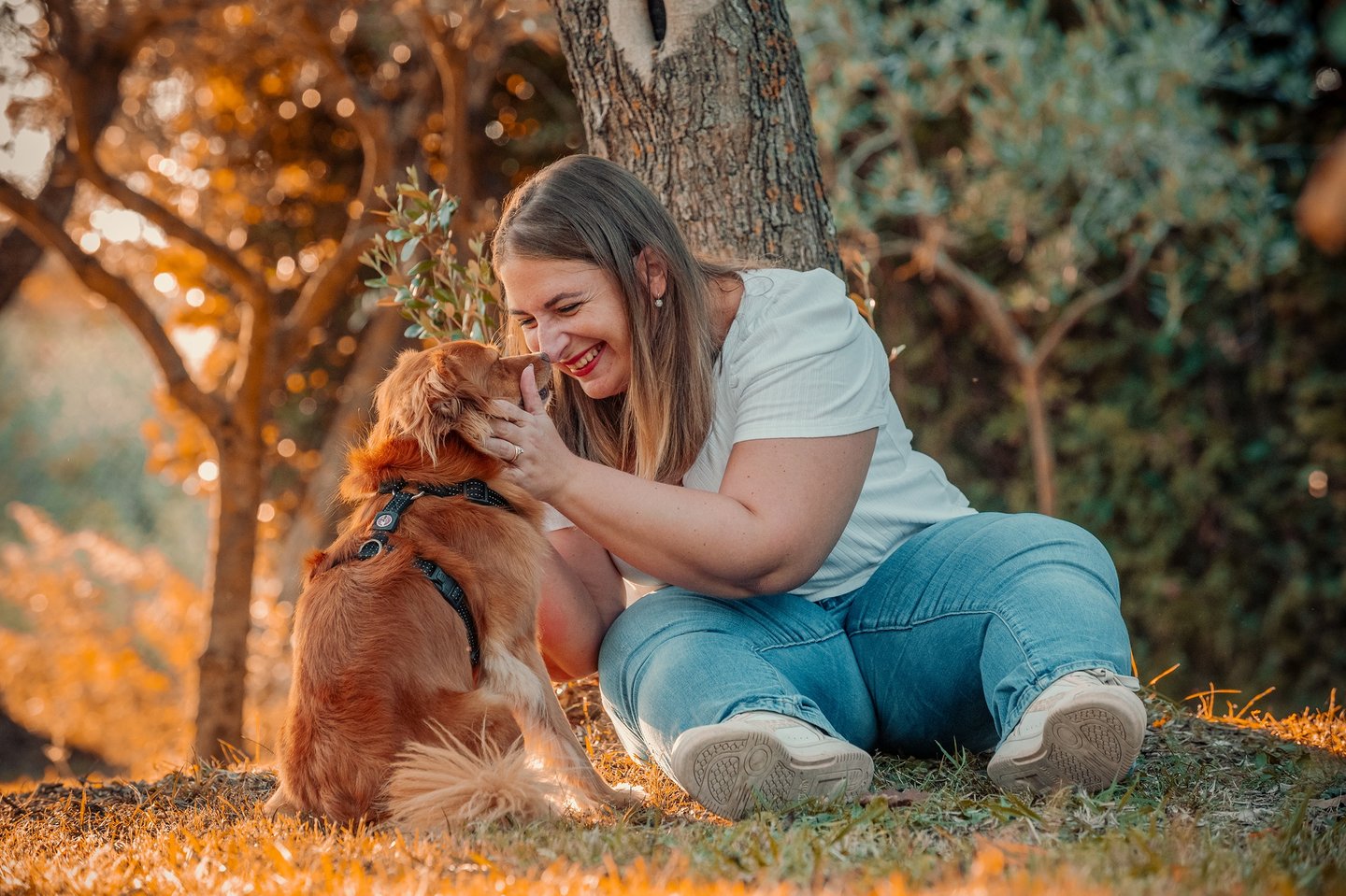 ragazza che sorride al proprio cucciolo seduta sotto un albero