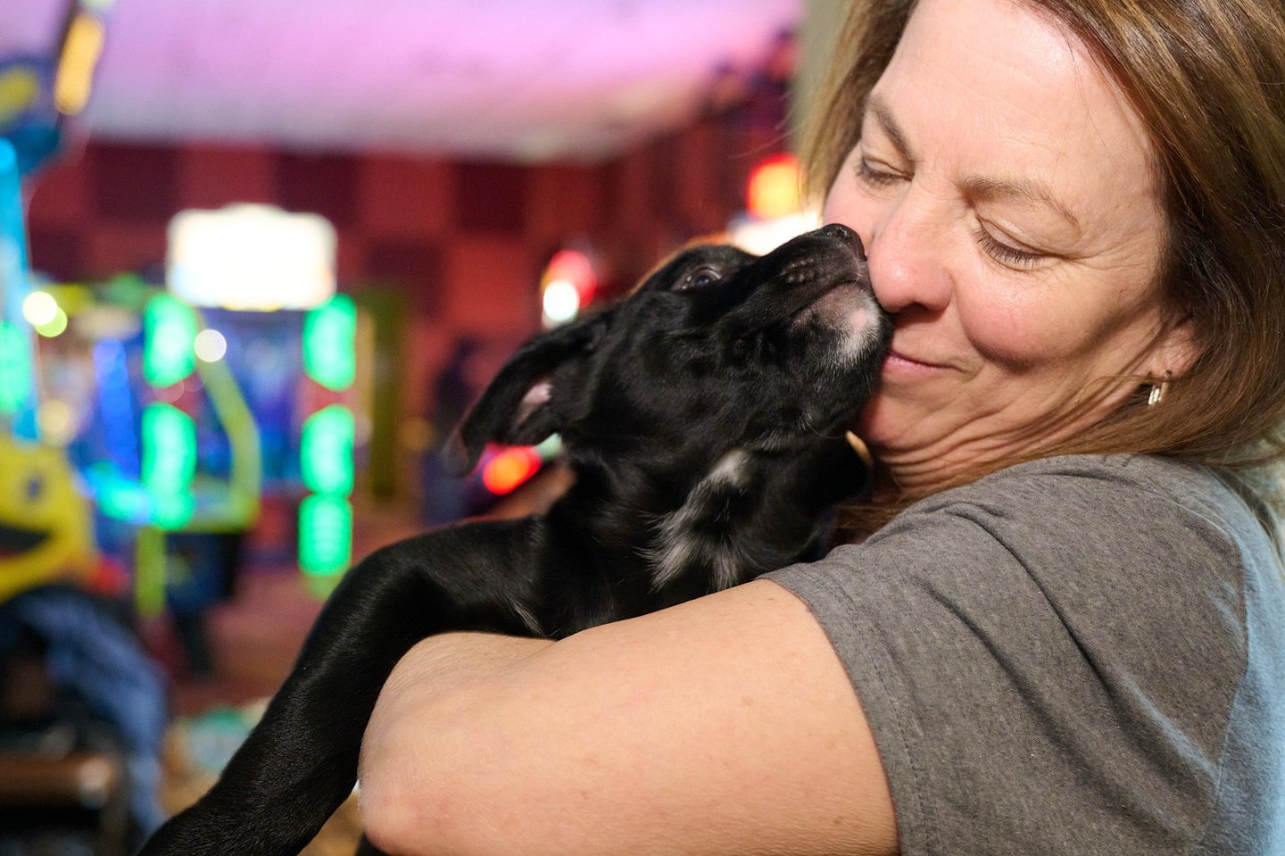 a woman is holding a black dog in her arms