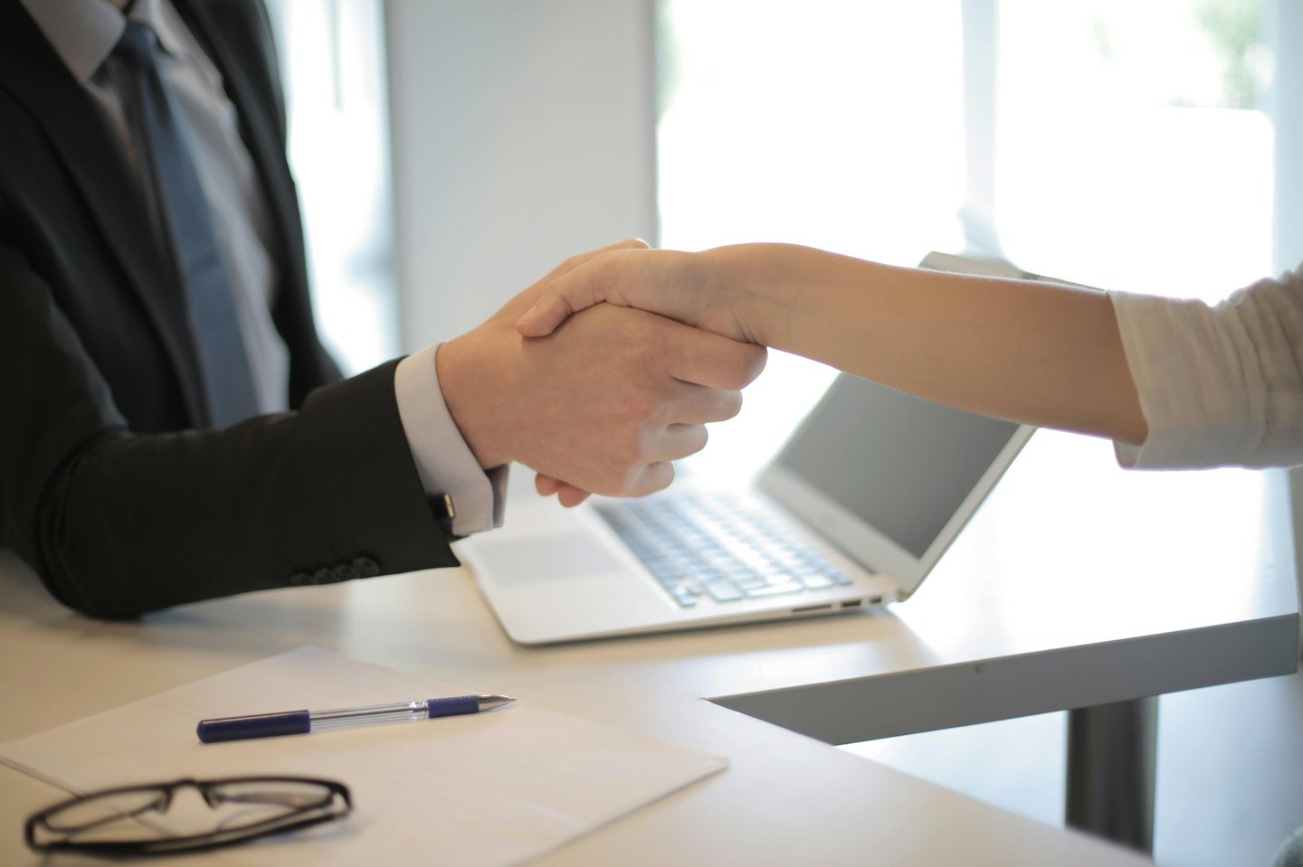 a man and woman shaking hands over a laptop