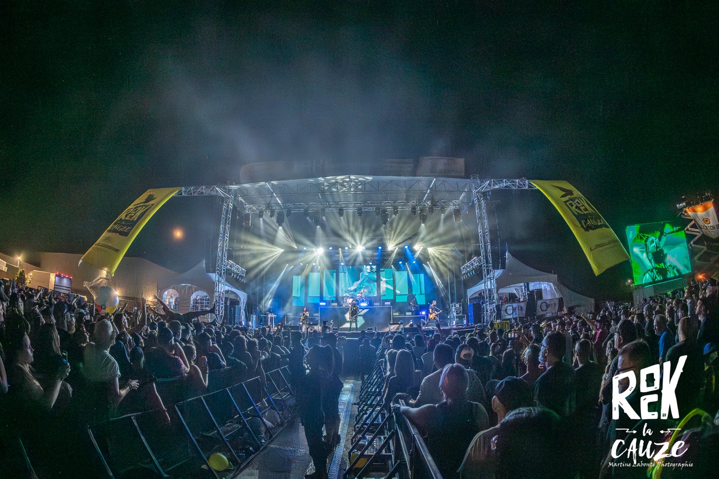 Live rock band performing on a lit outdoor stage at night during the Rok la Cauze music festival.