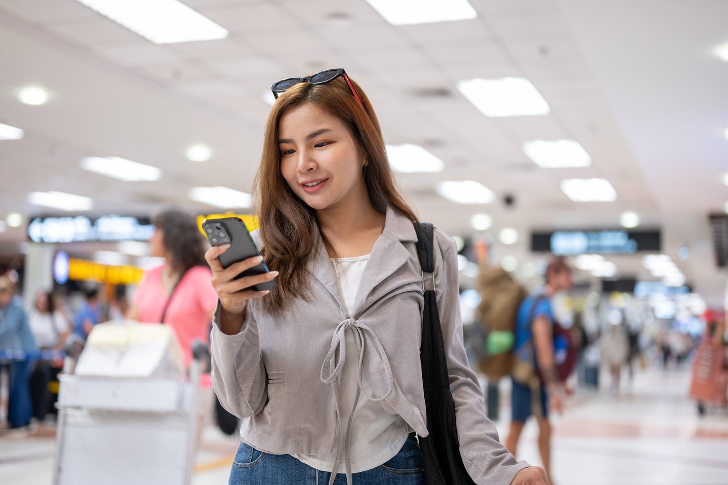 a woman in a gray jacket and sunglasses is holding a cell phone