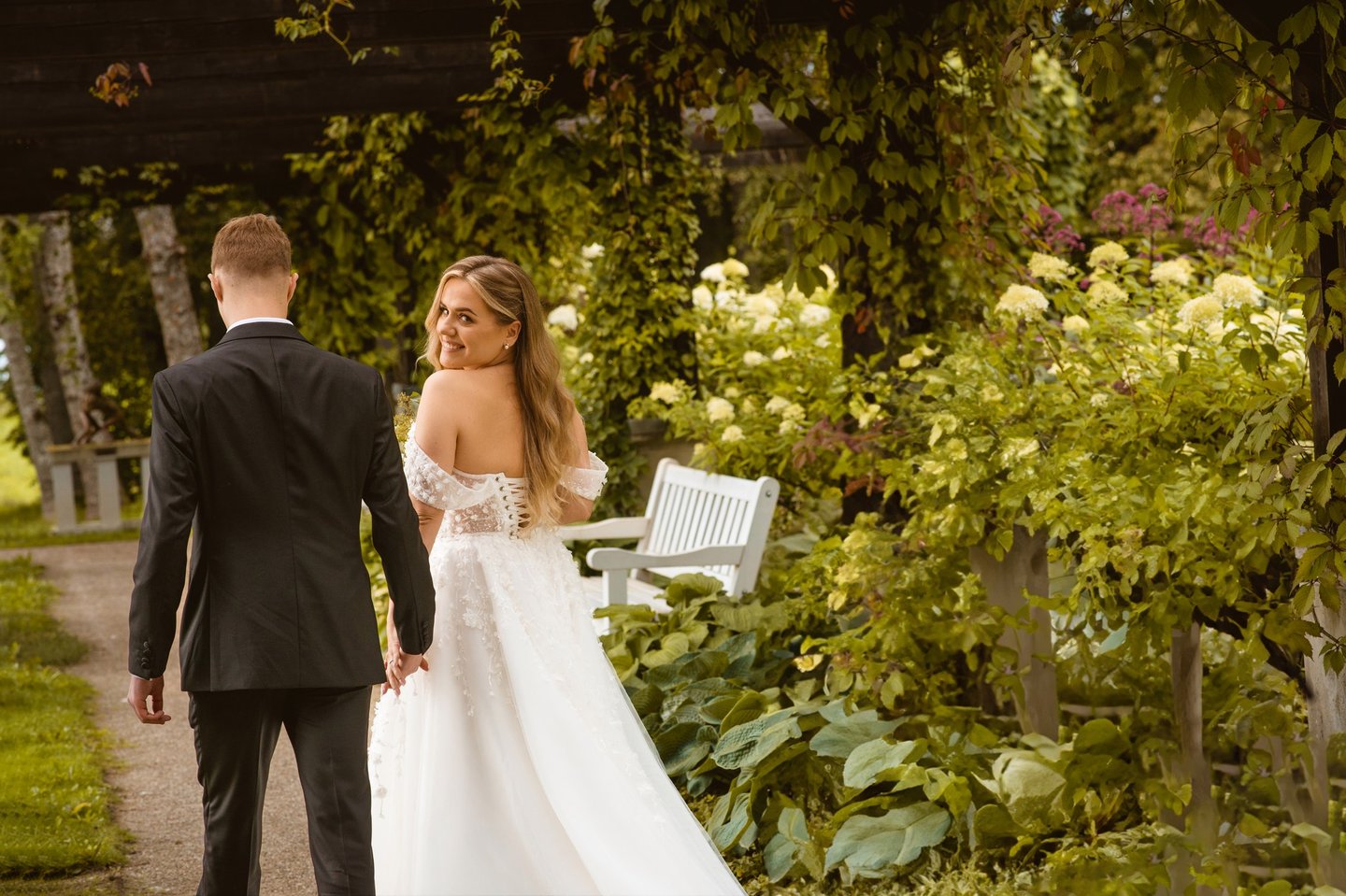 a bride and groom walking down a path