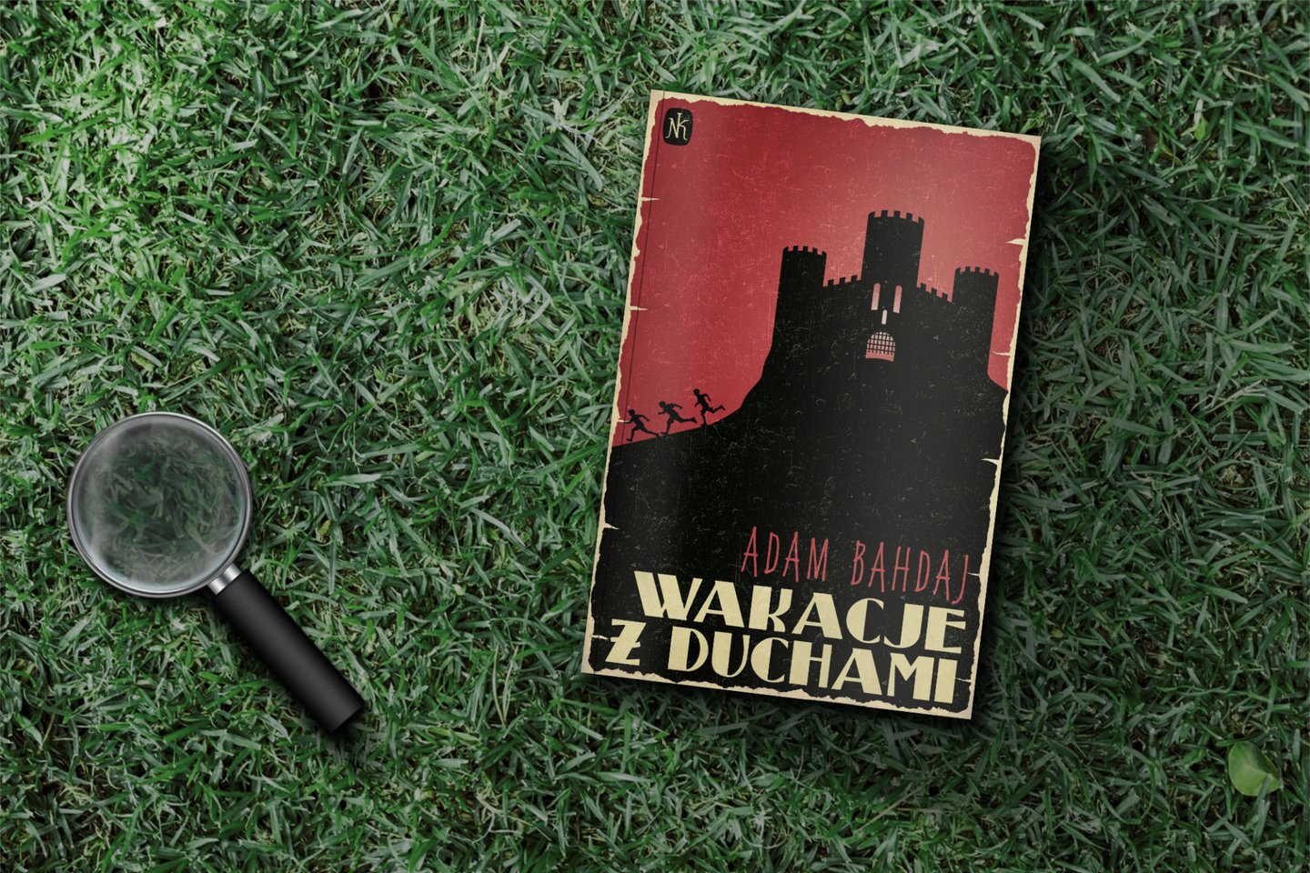 Book and magnifying glass laying on the grass