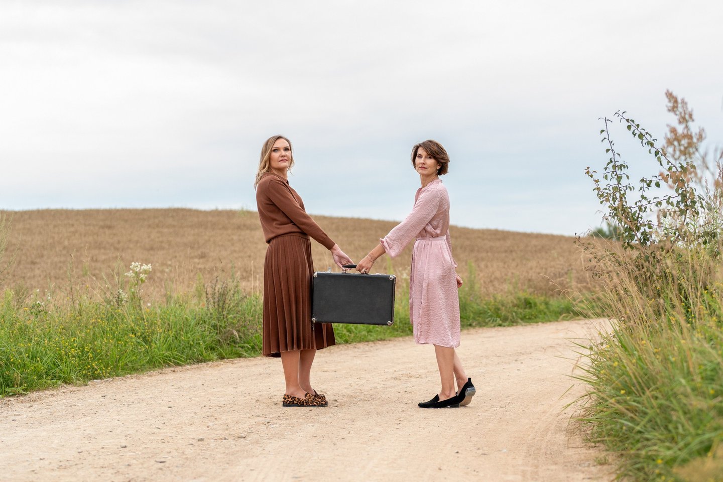 two women shaking hands on a dirt road