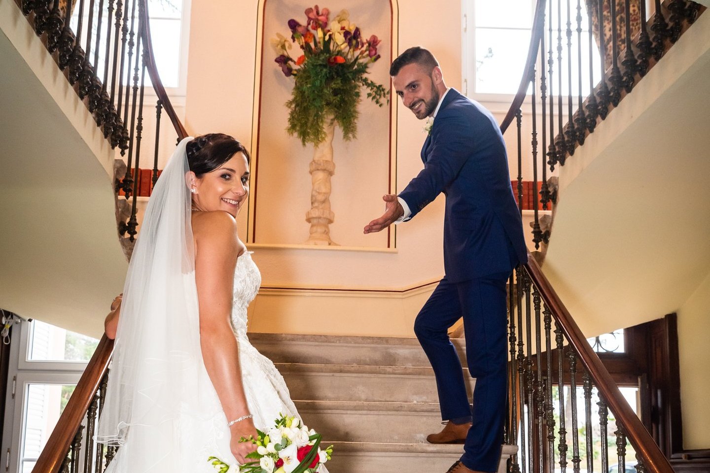 a bride and groom walking down the stairs of a staircase