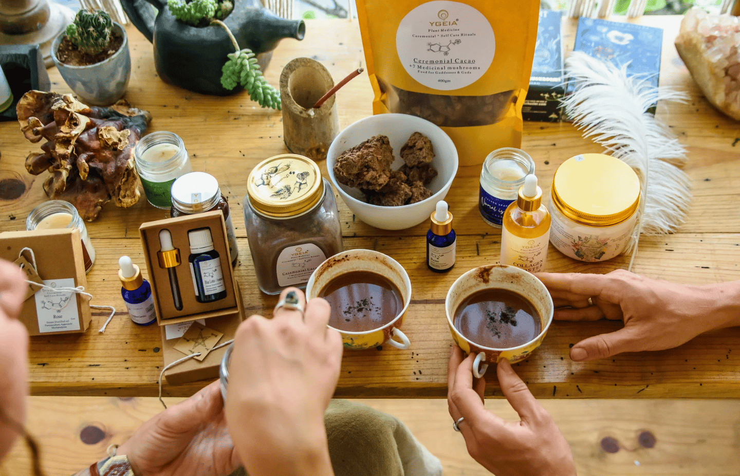 A wooden table with ceremonial cacao, medicinal mushroom supplements, and essential oils for holistic wellness.
