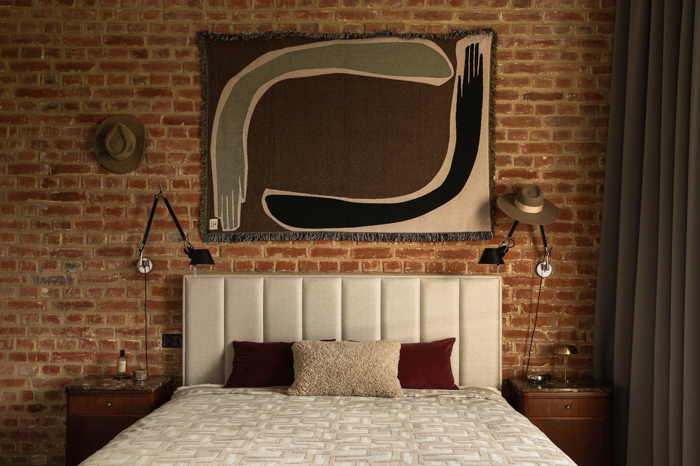 Sypialnia loft z ceglaną ścianą, beżowe łóżko i kilim.