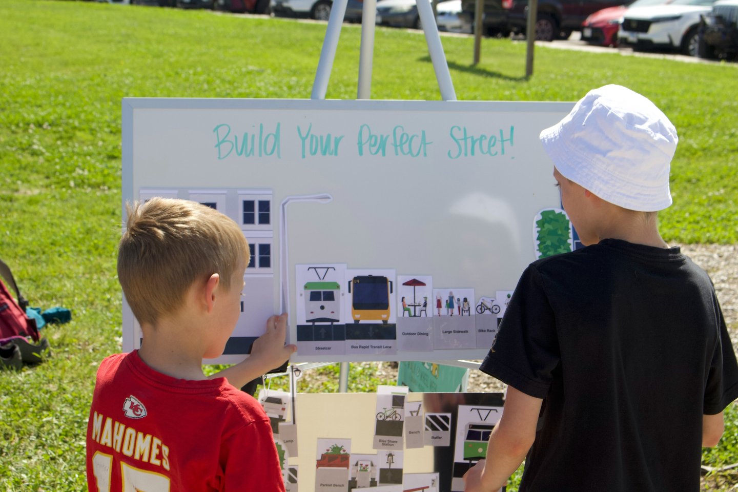 Two children at a whiteboard activity titled "Build Your Perfect Street!"