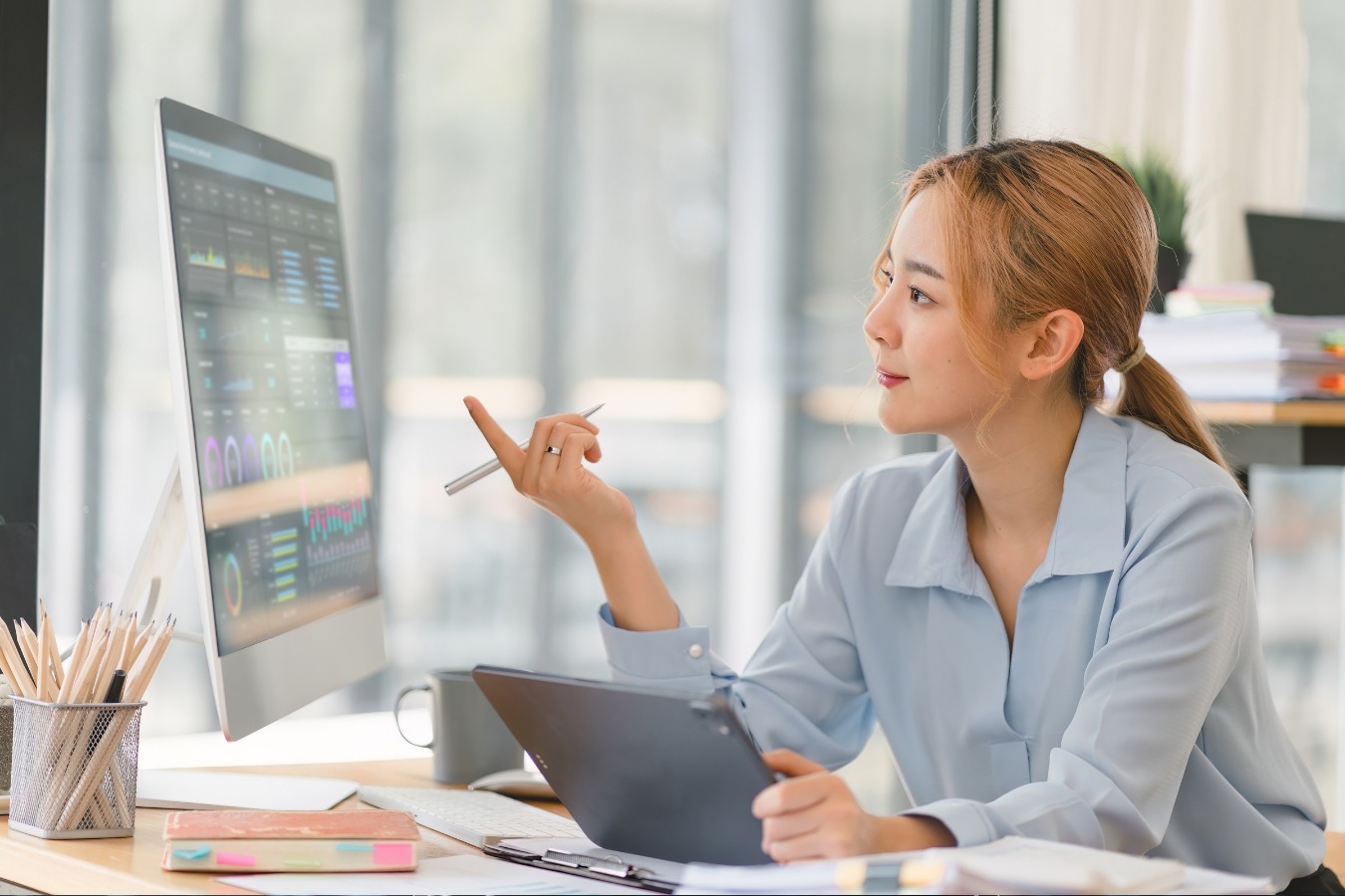 a woman sitting at a desk with a computer and a pen-ai integrated digital marketing