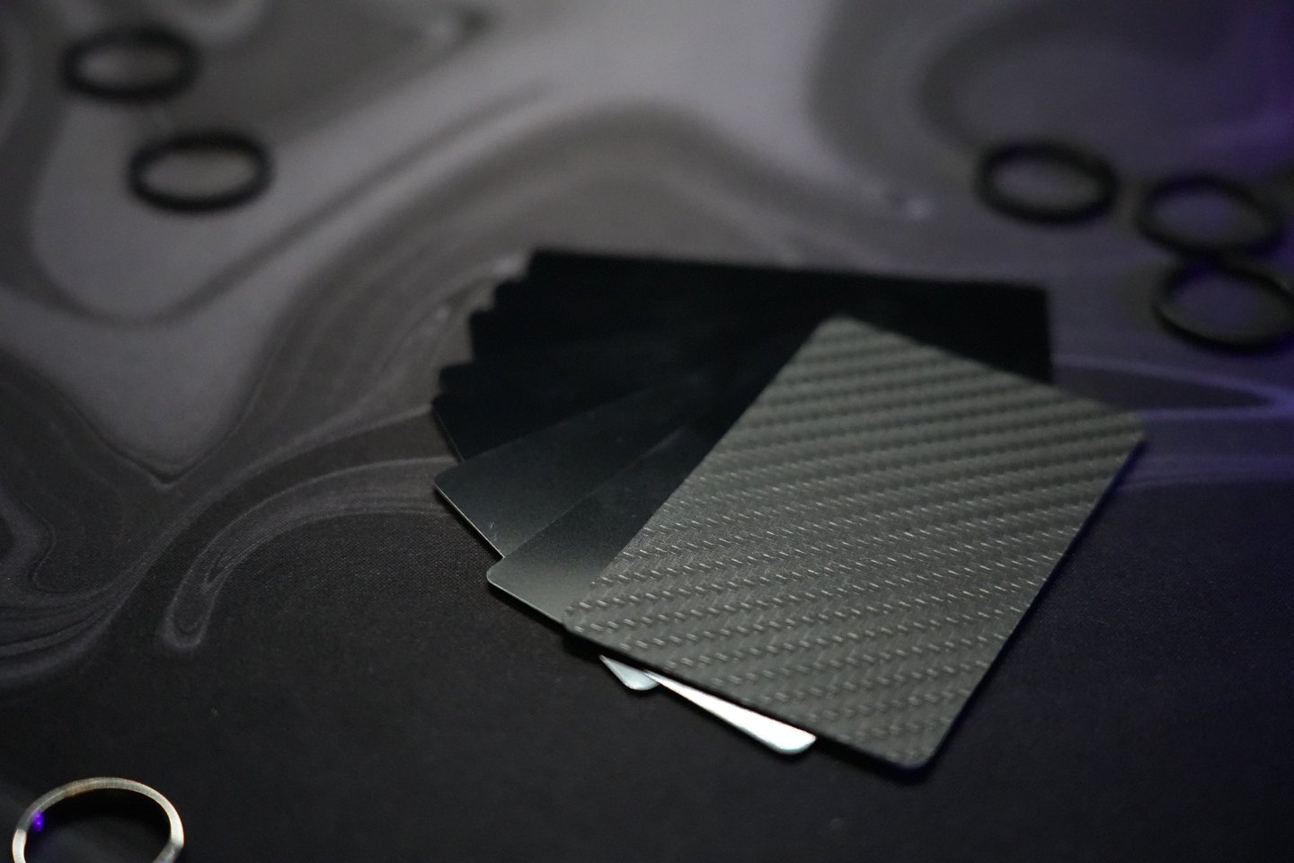 A stack of premium carbon fiber credit cards and metal wallet cards on a dark marble surface.