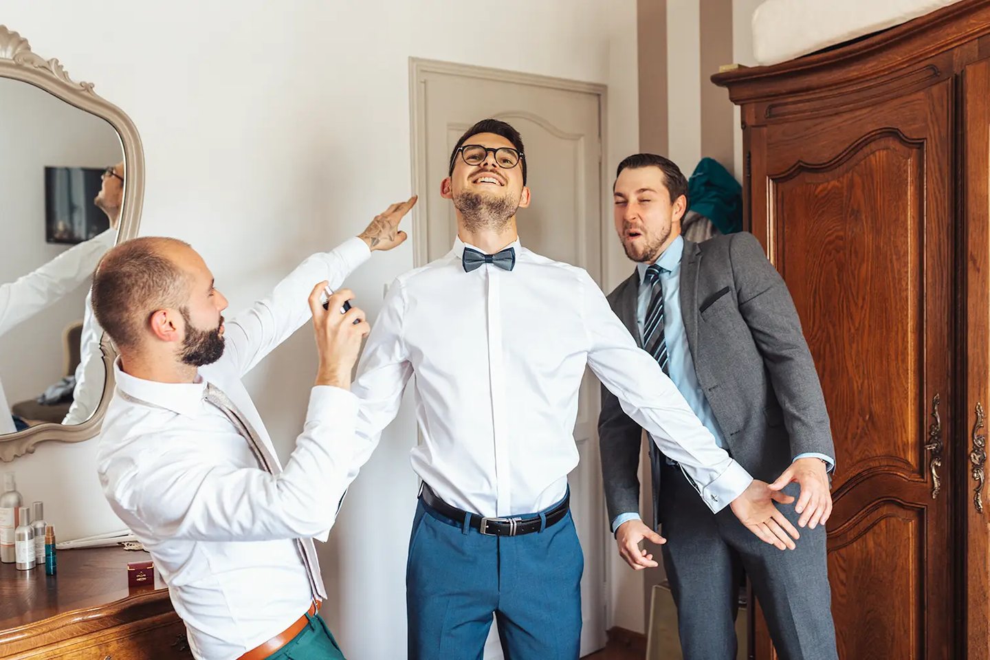 Jeune marié entouré de deux amis pendant les préparatifs dans une ambiance fun et pleine de joie.