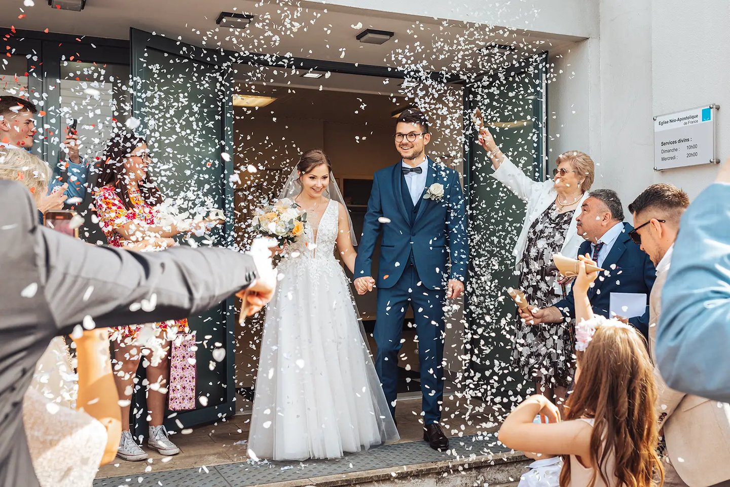 Mariés qui sortent de la cérémonie religieuse sous une pluie de confettis.