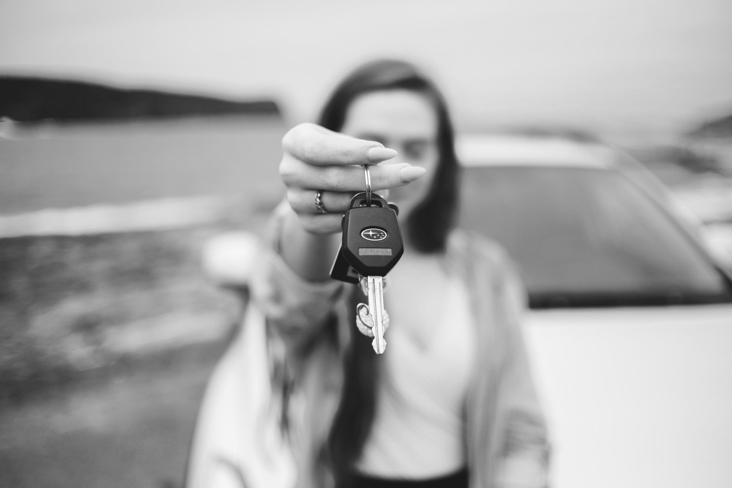 grayscale photo of a woman holding a keychain and a car keys