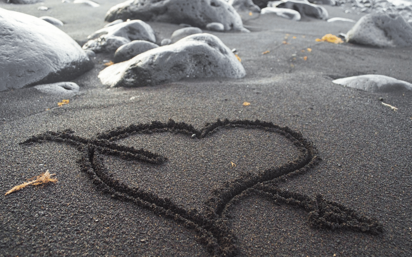 Heart drawn in dark sand on a California beach, symbolizing a romantic couples getaway