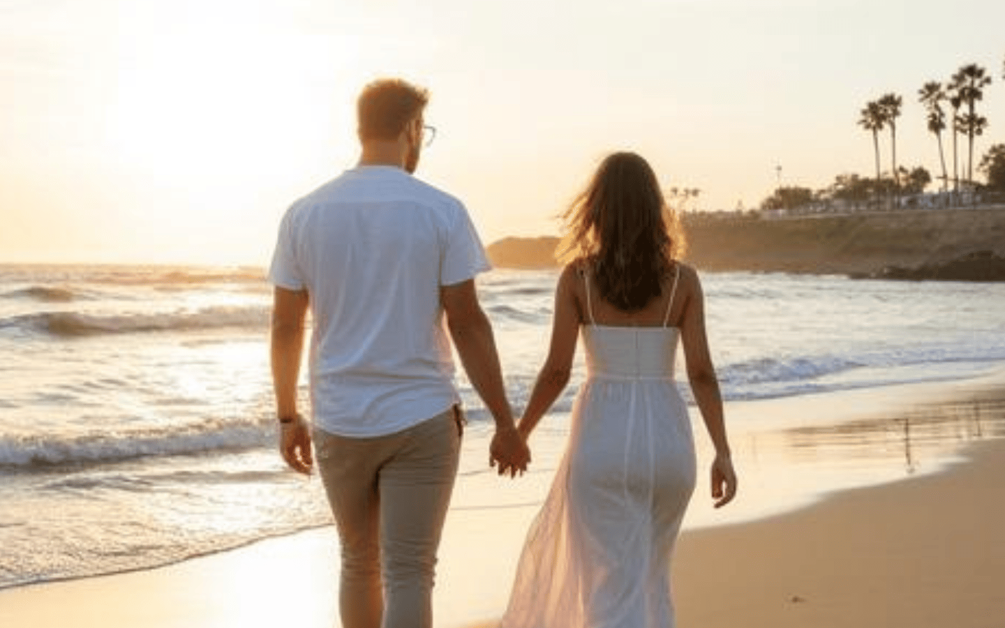 Couple holding hands while walking along the beach at sunset in Santa Barbara, California