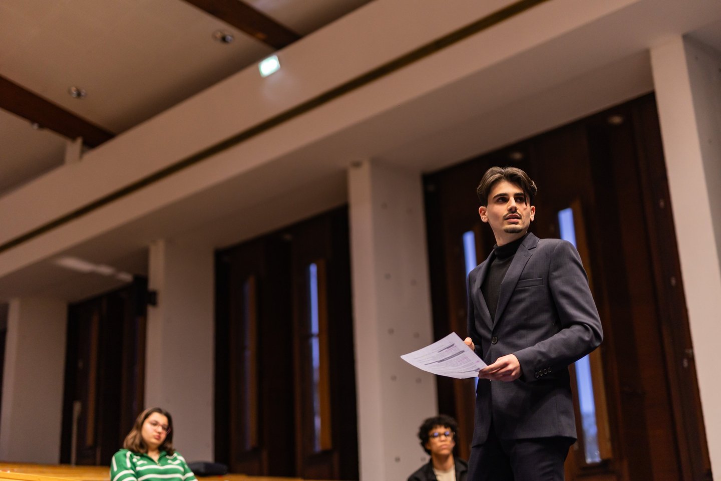 a man in a suit and tie is standing in front of a group of people
