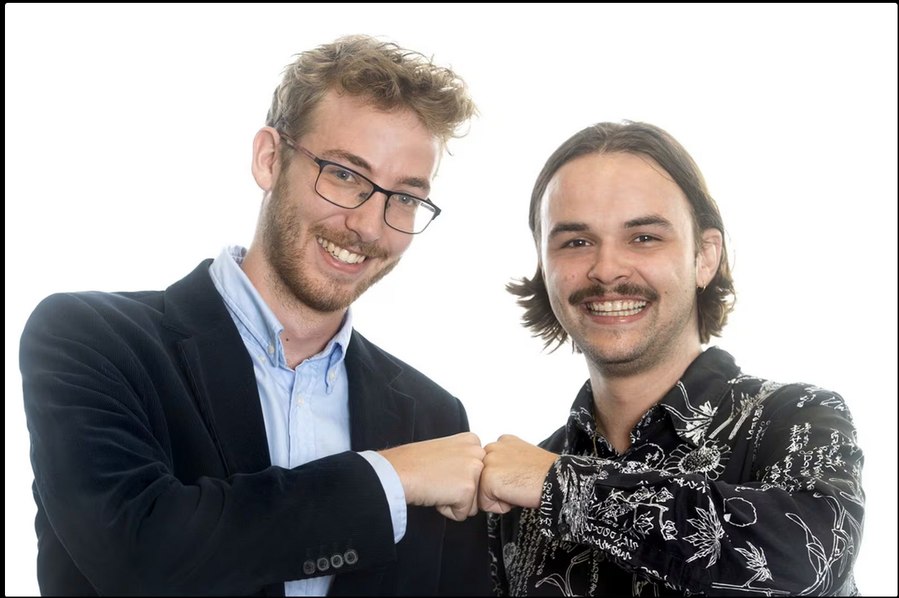 a man in a suit and tie is smiling and pointing at the camera