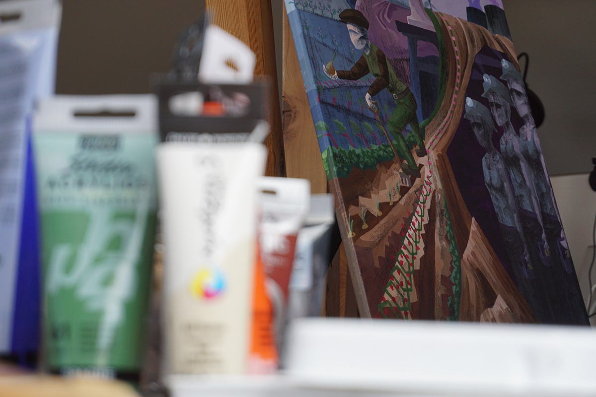A painted canvas in a cubist or constructivist style depicting agriculture is displayed in focus.