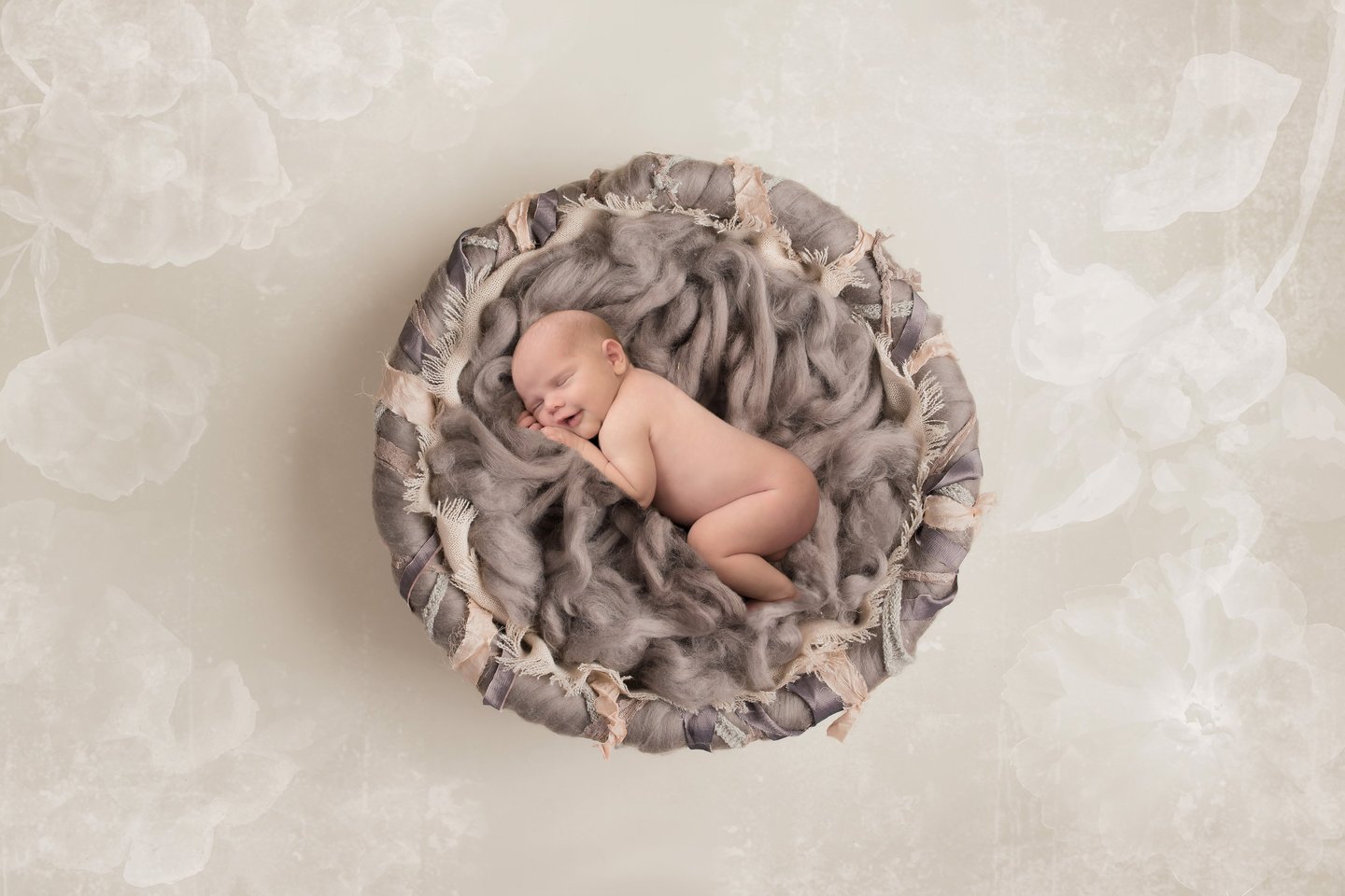 A newborn studio portrait features a peacefully sleeping baby, elegantly posed with soft fluffy wool and delicate lighting.