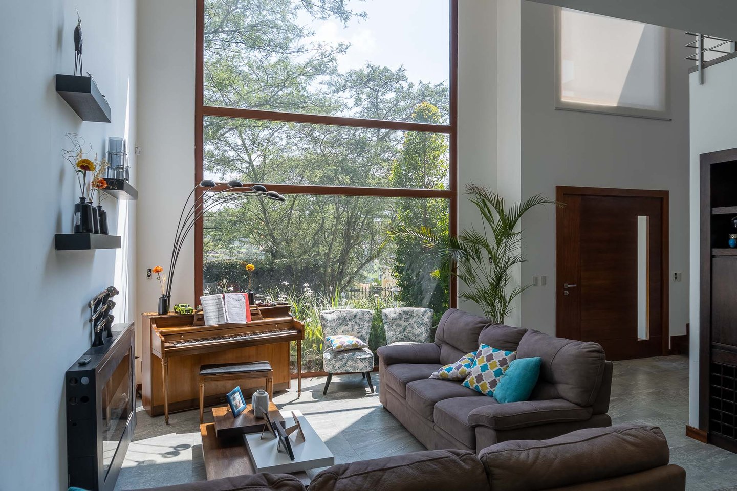 fotografía inmobiliaria quito ecuador tumbaco gran sala de estar con muebles, piano y un gran ventanal con luz natural