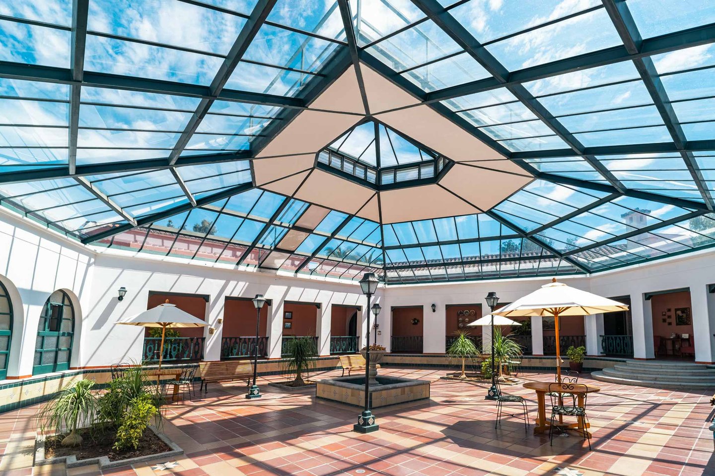 Plaza interna con tragaluz y grandes ventanales zona de descanso con sombrillas y sillas inmueble en Quito Ecuador