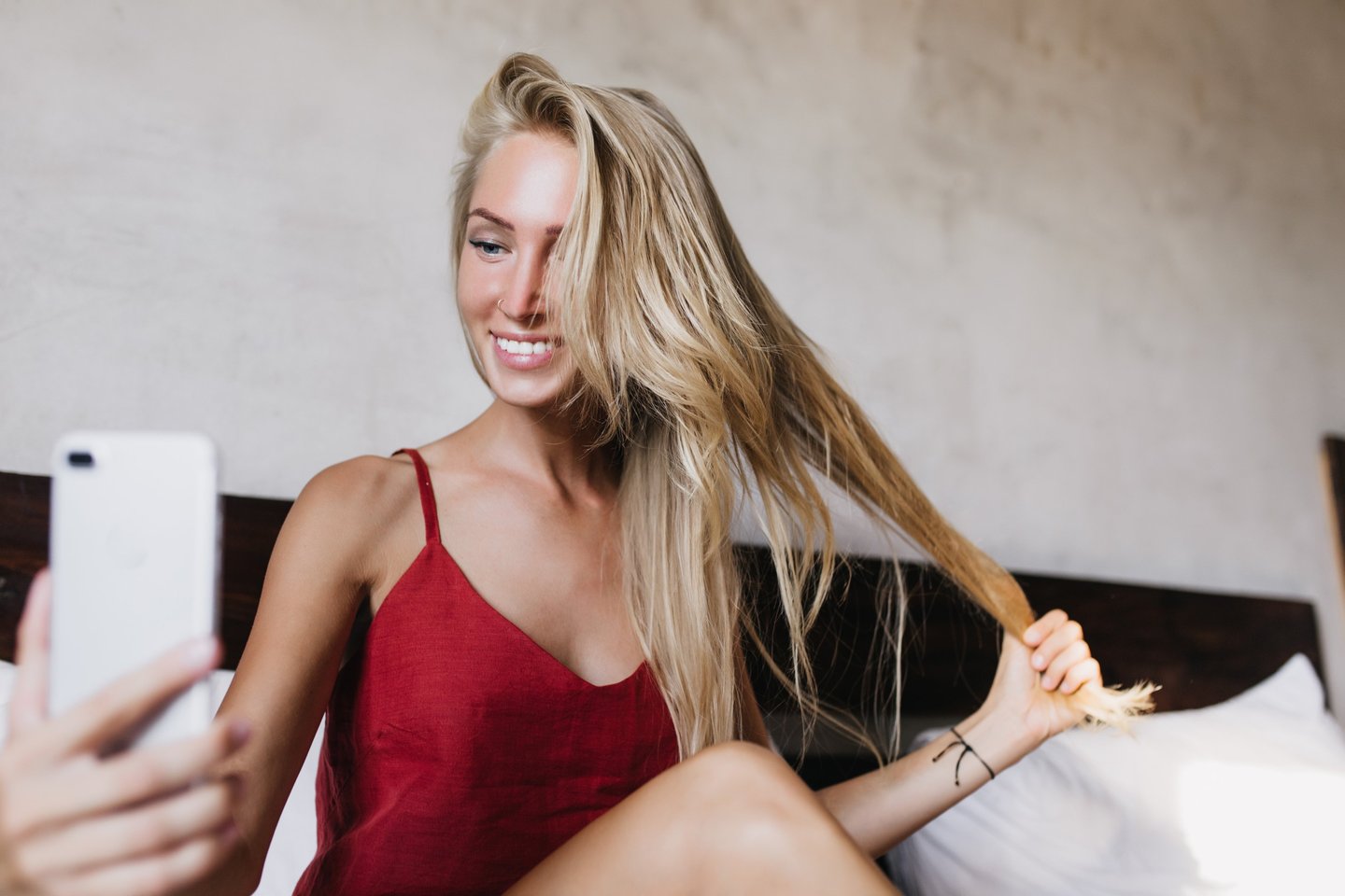 Smiling female content creator taking a selfie at home while holding her long hair