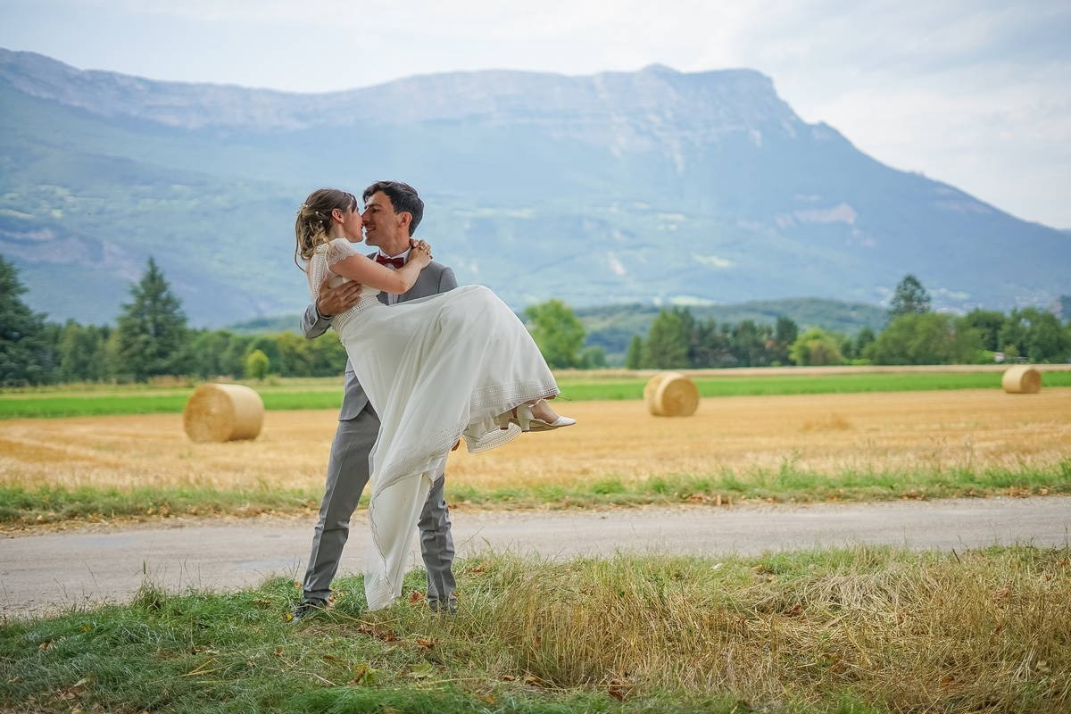 Photo de mariage, le marié porte la mariée dans ses bras dans un champ