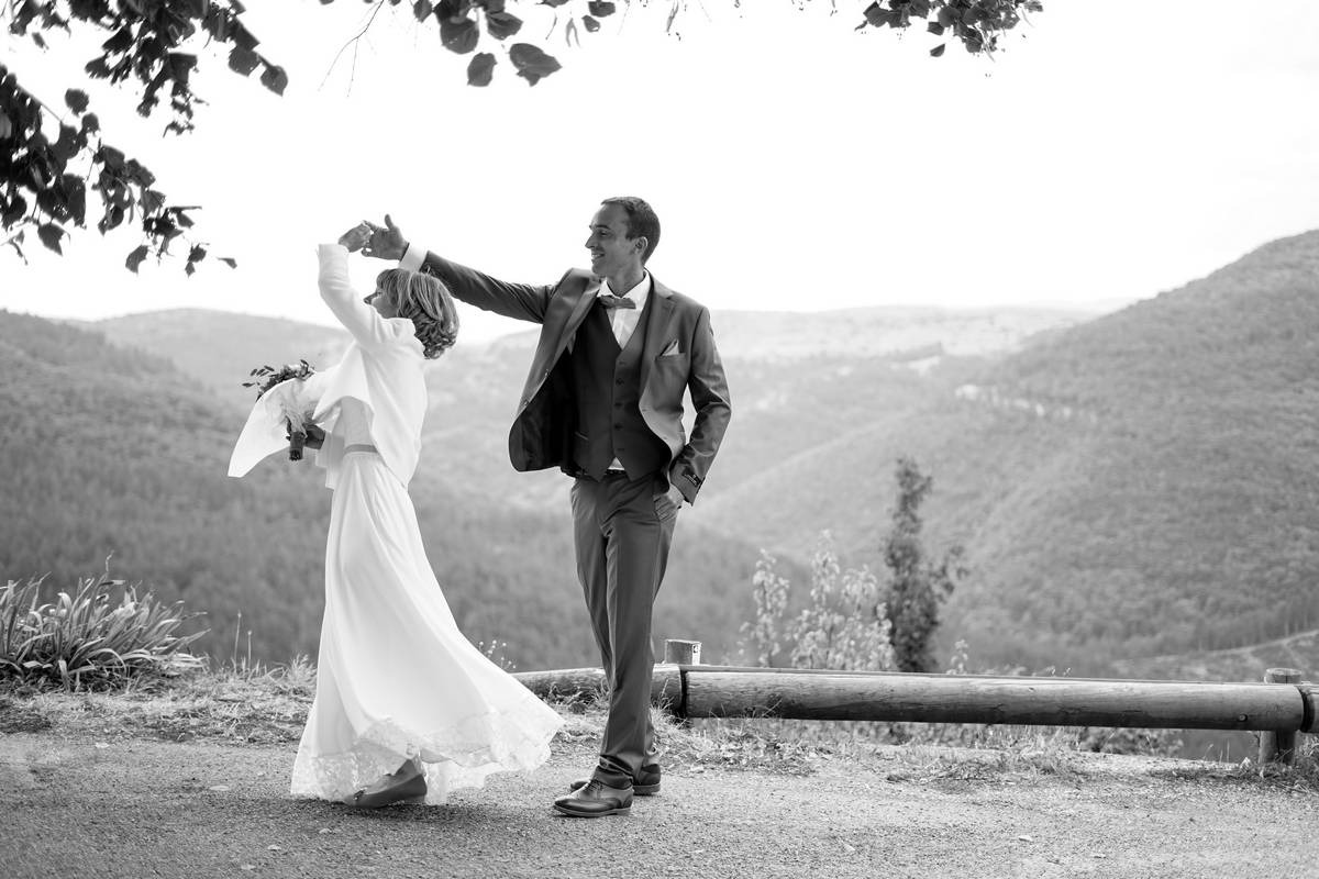 Photo en noir et blanc de mariés qui dansent devant la mairie lors de leur journée de mariage 