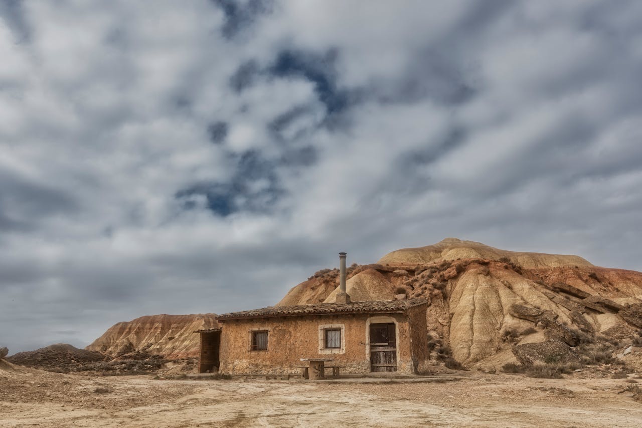 Antigua cabaña de piedra solitaria junto a cerros erosionados en el paisaje desértico de Bardenas