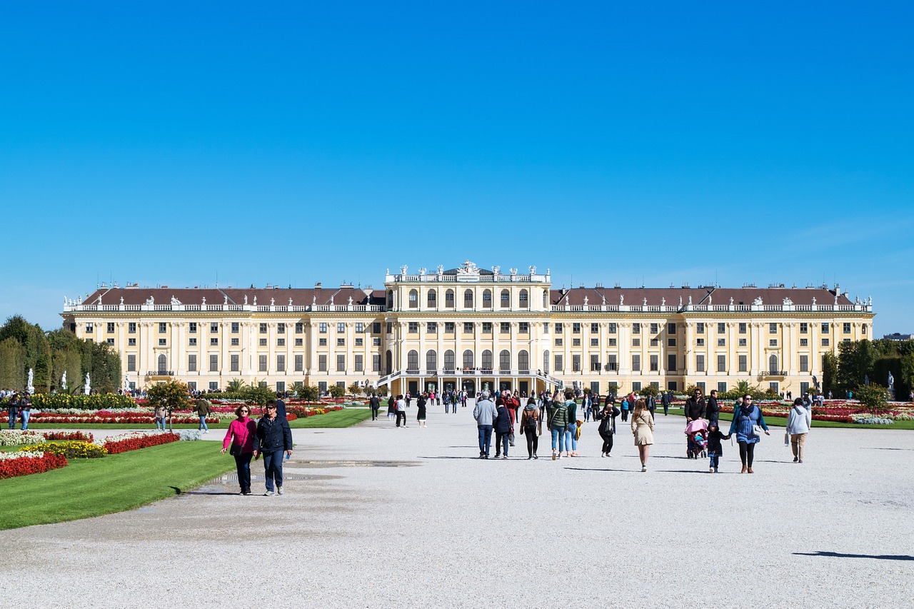 Fachada principal del Palacio de Schönbrunn en Viena con turistas paseando por los jardines