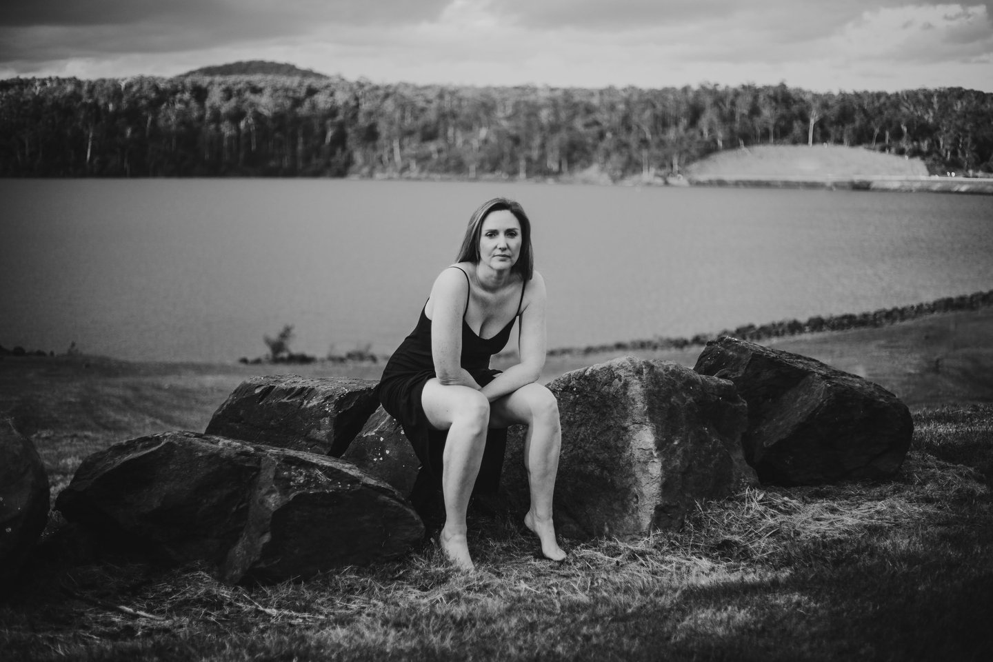 a woman sitting on a rock next to a lake