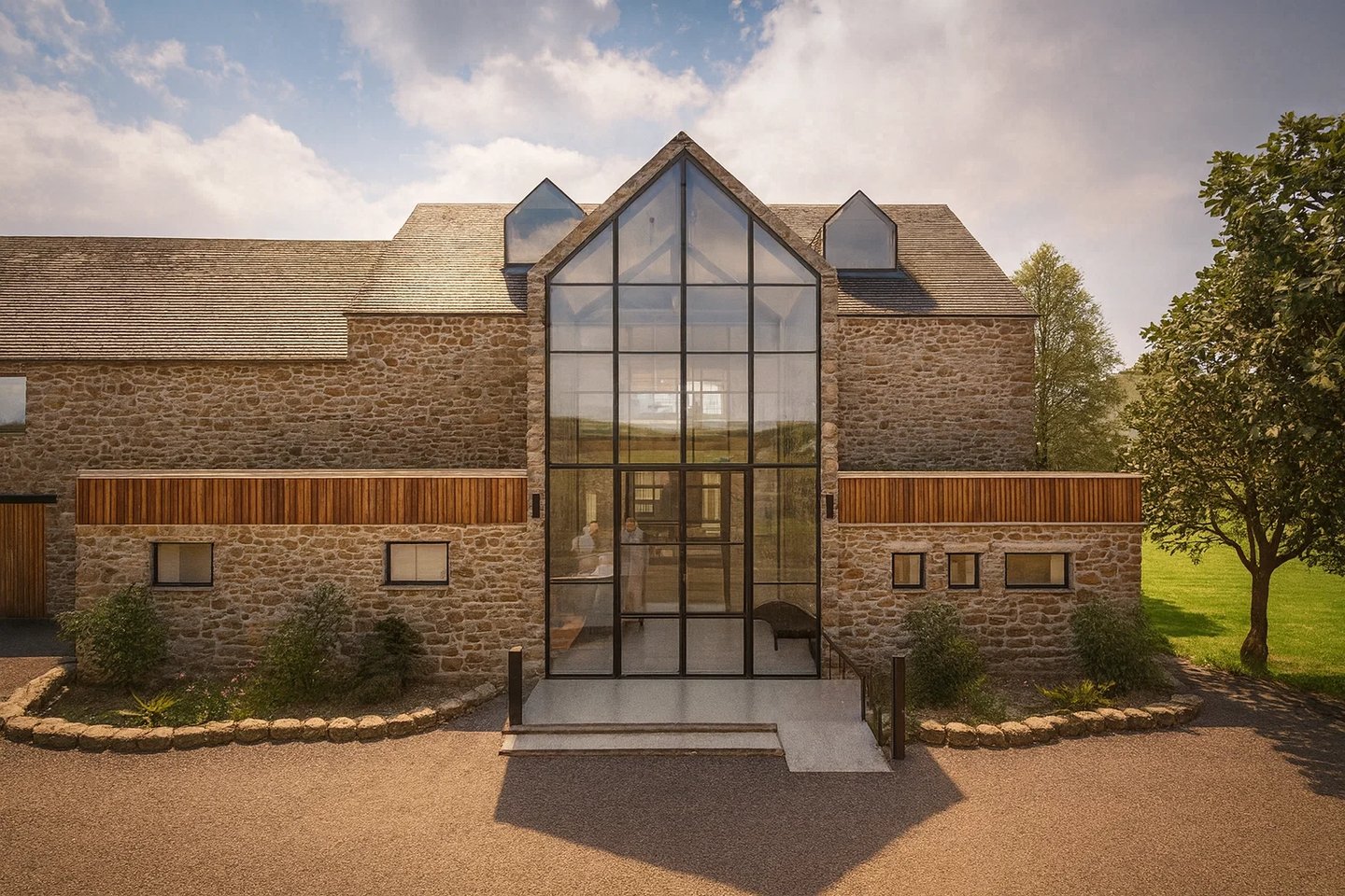 Modern stone barn conversion featuring a large gabled glass entrance and contemporary architecture.