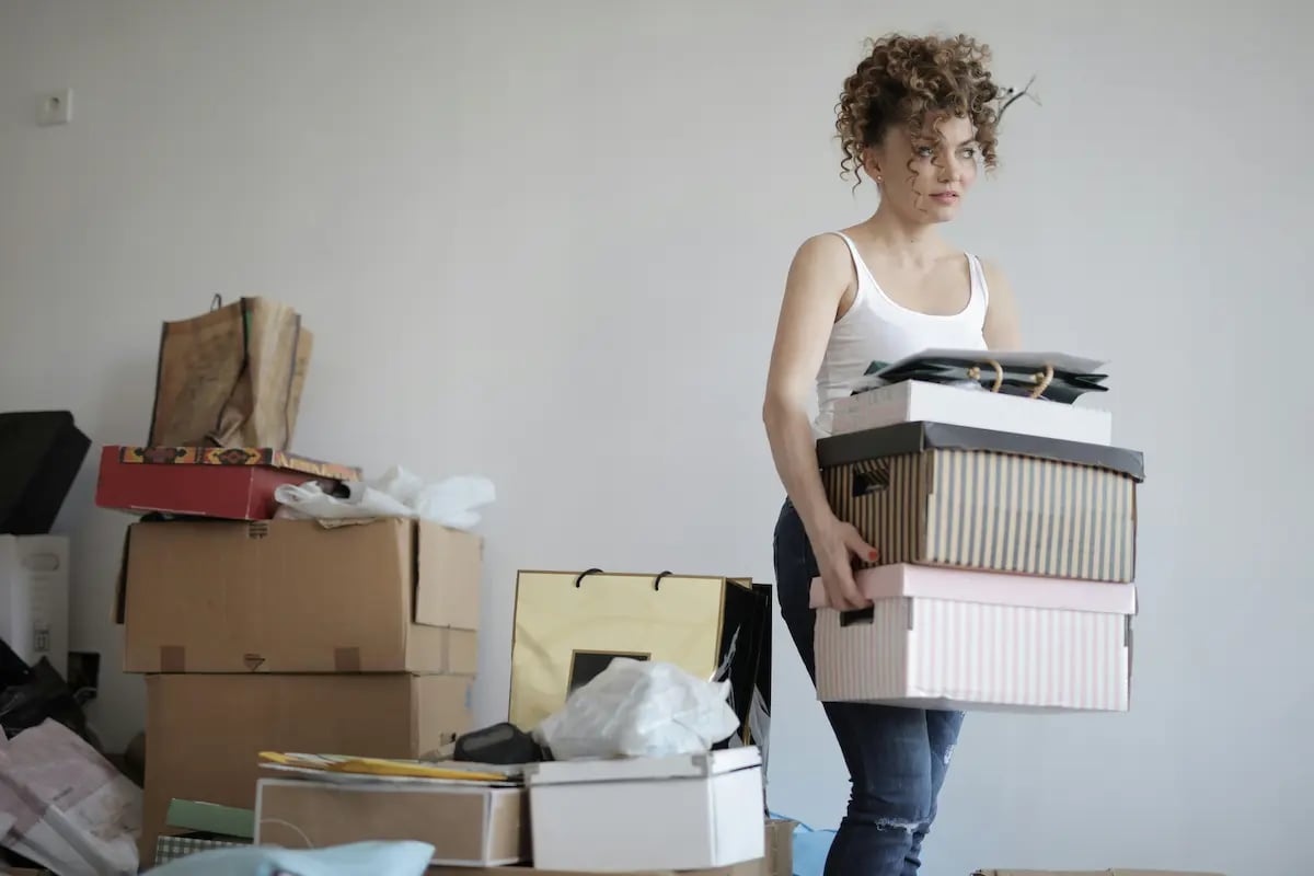 A woman carrying a stack of decorative boxes while moving into a new apartment.