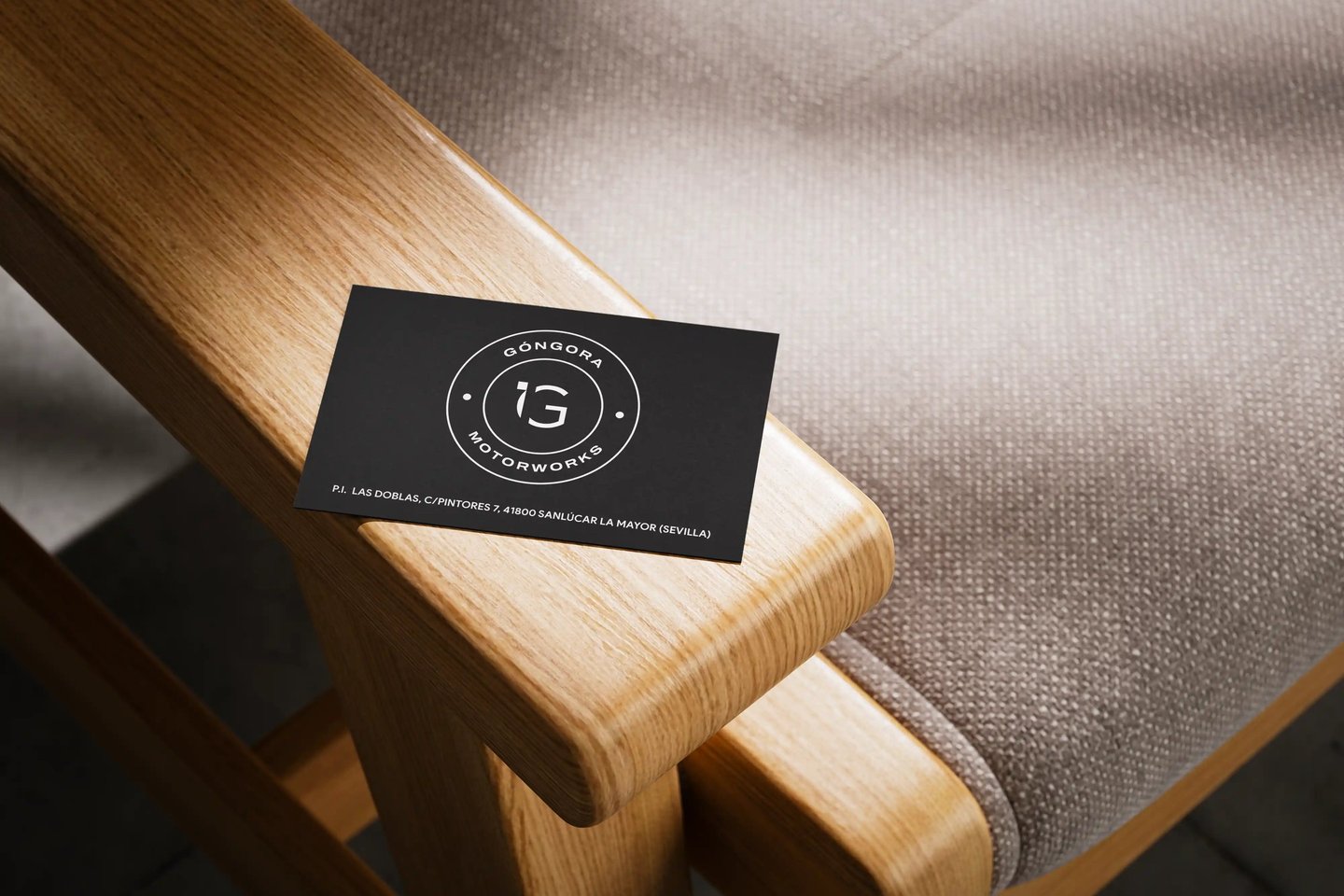 Tarjeta de visita de Góngora Motorworks sobre el brazo de madera de una silla