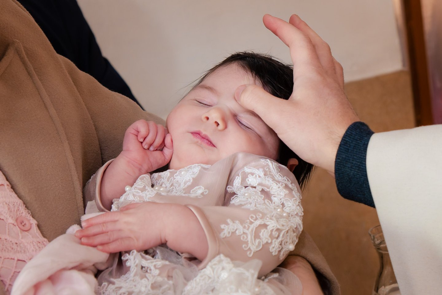 majka drži bebu u svojim rukama za vrijeme obreda krštenja