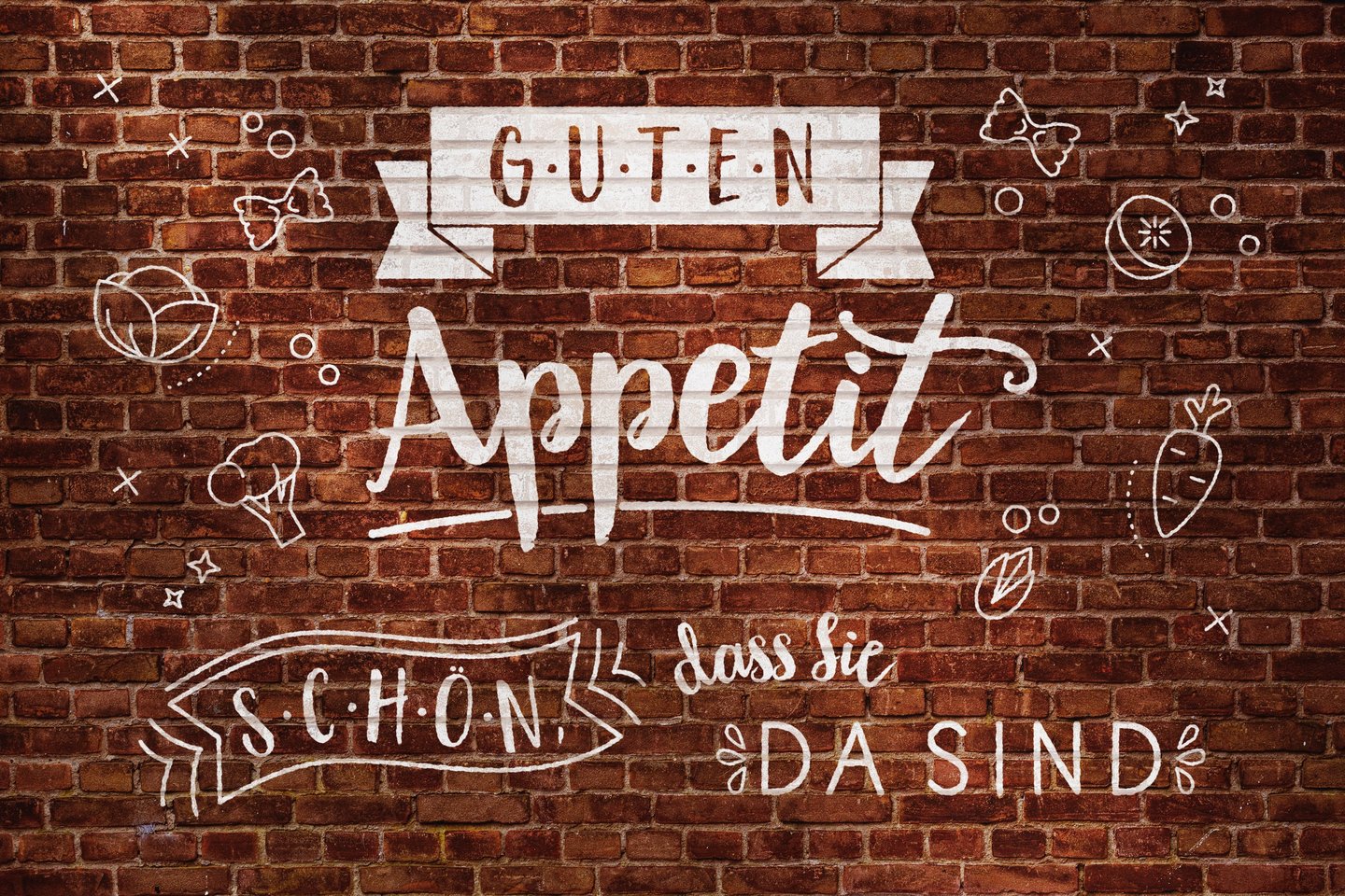 White Guten Appetit lettering and food doodles on a rustic red brick wall.