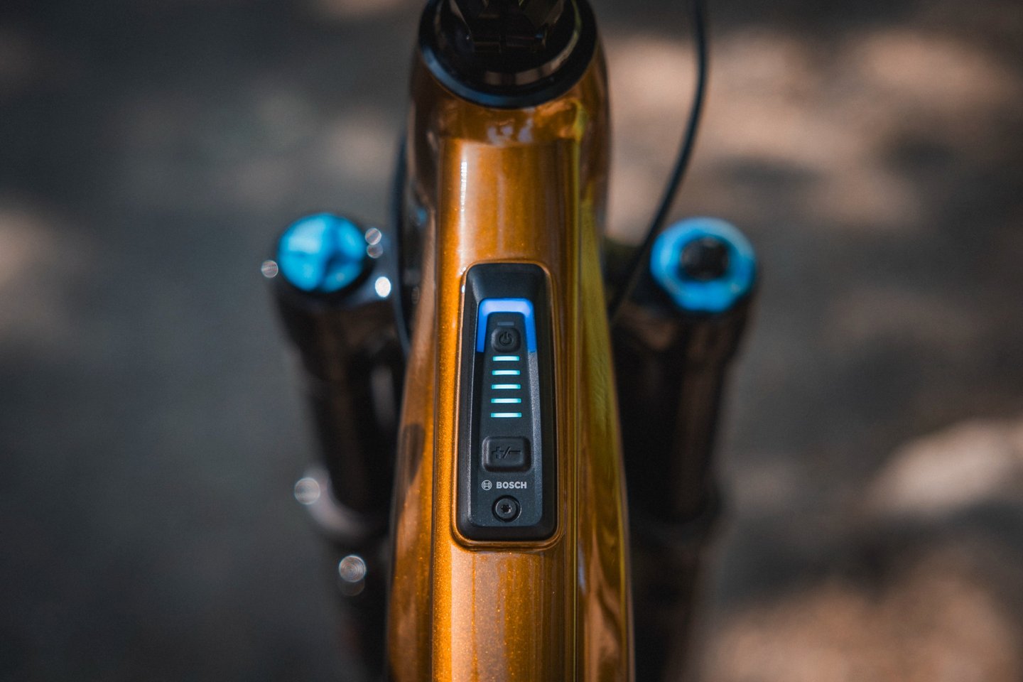 Close-up of a Bosch System Controller integrated into the top tube of an orange e-bike frame.