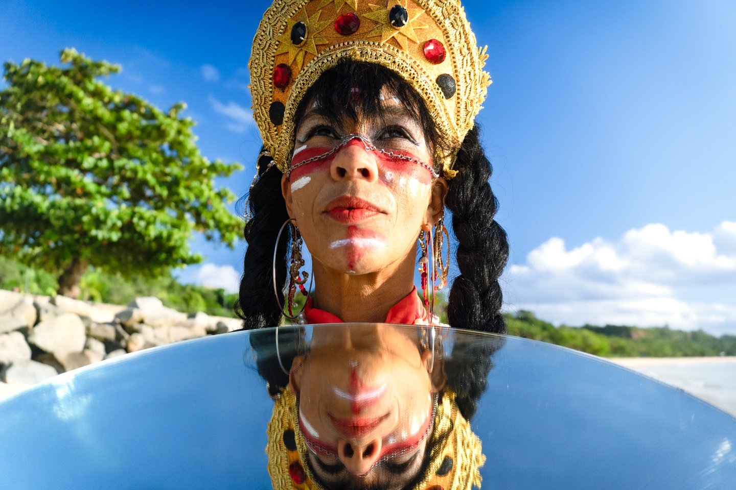 Mulher com coroa olha para o horizonte abaixo seu reflexo no espelho