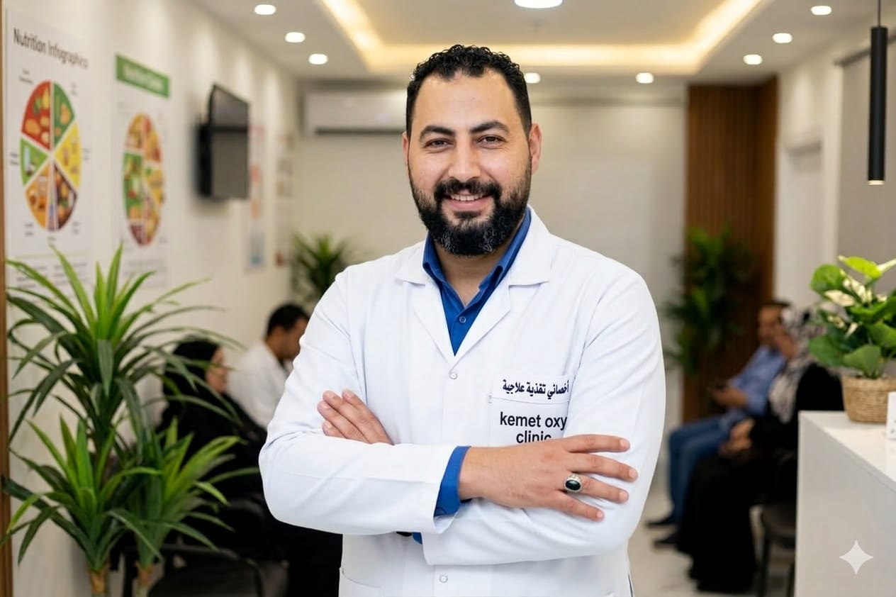 Smiling Mohamed Hassan, Therapeutic  in a white coat at Kemet Oxy Clinic standing with arms crossed.