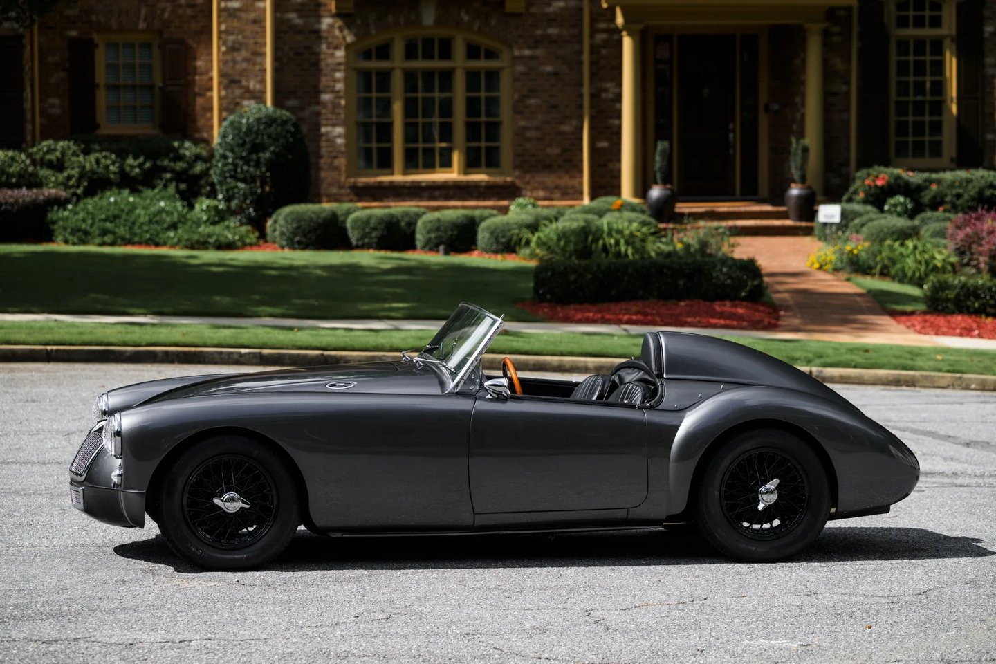 A photo of a 1958 MG MGA Roadster in a garden setting.