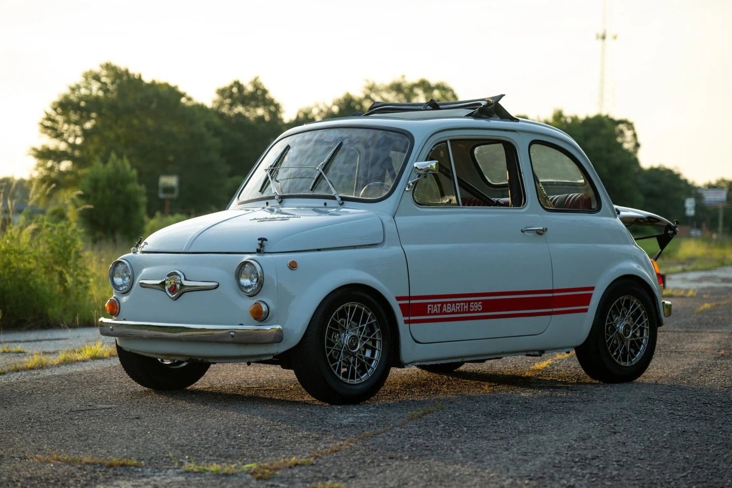 A photo of a blue grey 1974 Fiat 595 SS Abarth in a wooded setting at dusk.