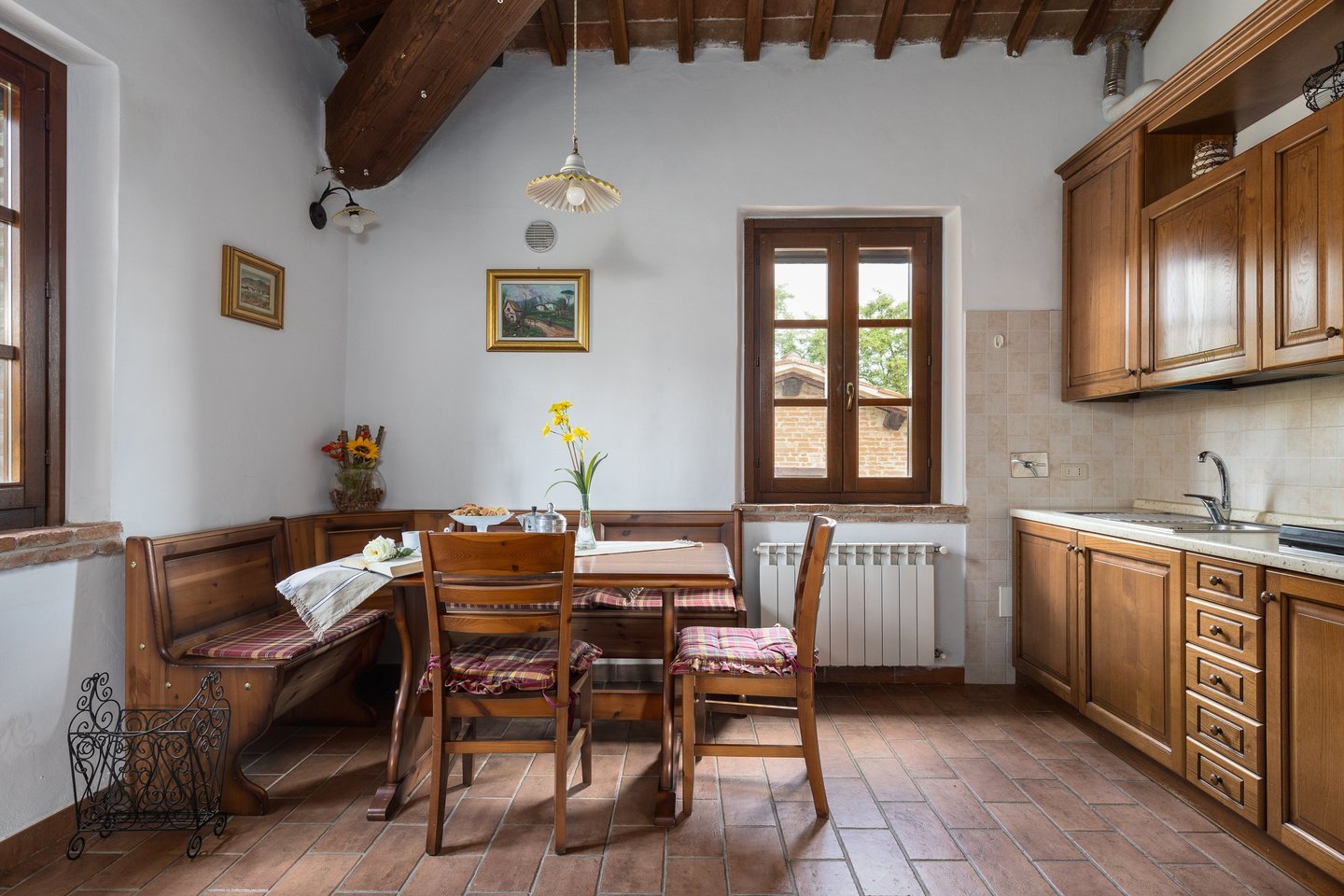 Rustic Italian kitchen with wood cabinets, terracotta tile floors, and a wooden breakfast nook.