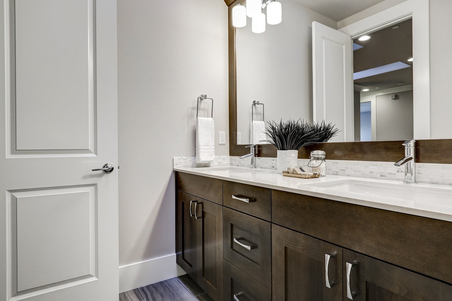 Modern bathroom remodel featuring a dark wood double vanity with white quartz countertops and large mirror.