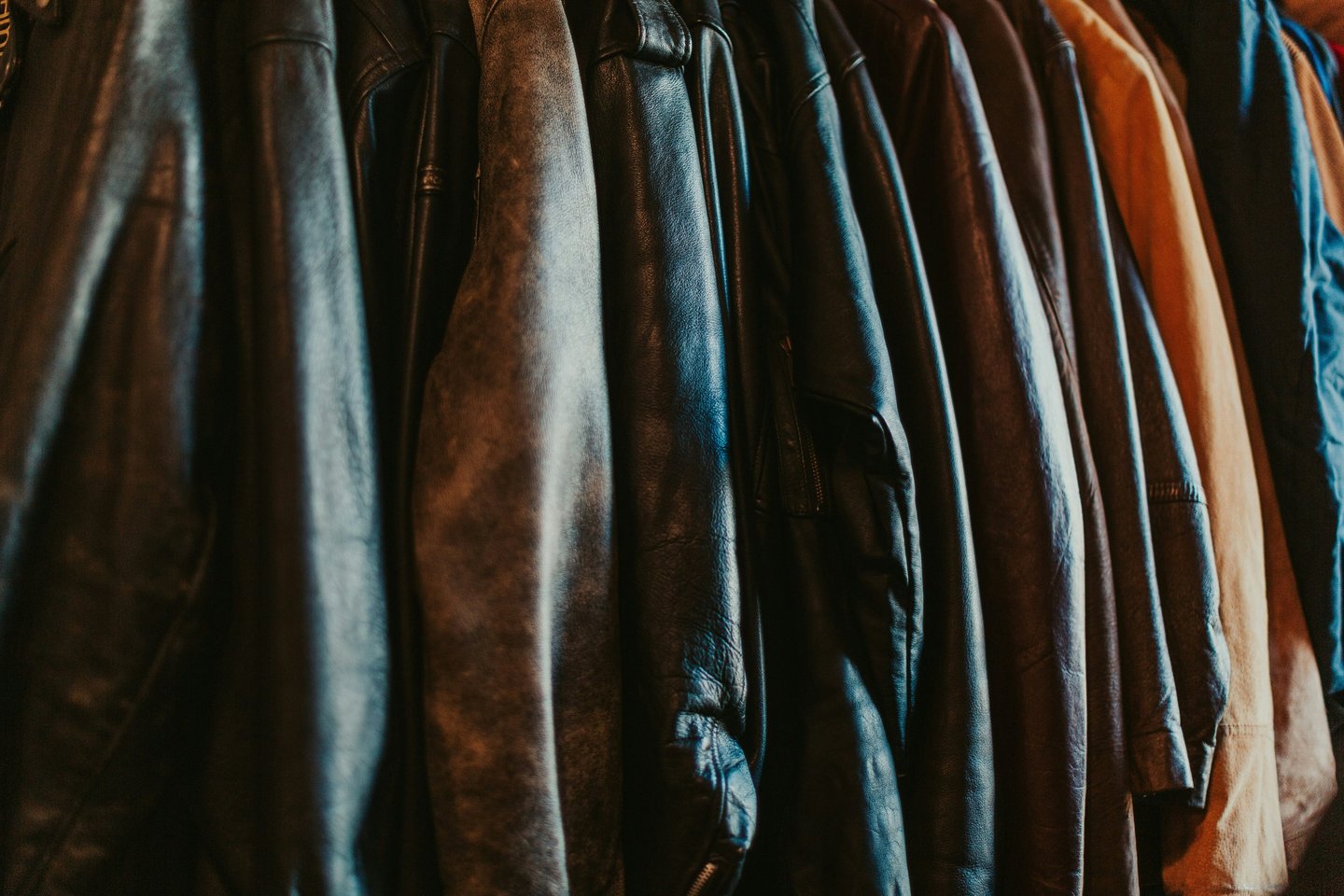 A collection of vintage leather jackets hanging on a rack in a boutique clothing store.