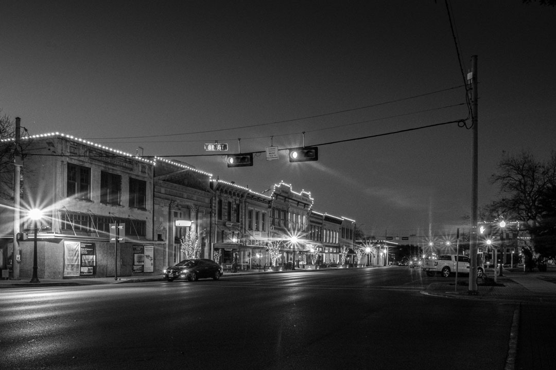 Night photo of Austin Ave in Georgetown, Texas, with it's historic buildings illuminated by streetlights 
