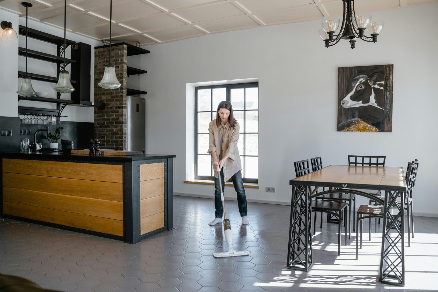 a woman in a kitchen with a mop cleaning the floor
